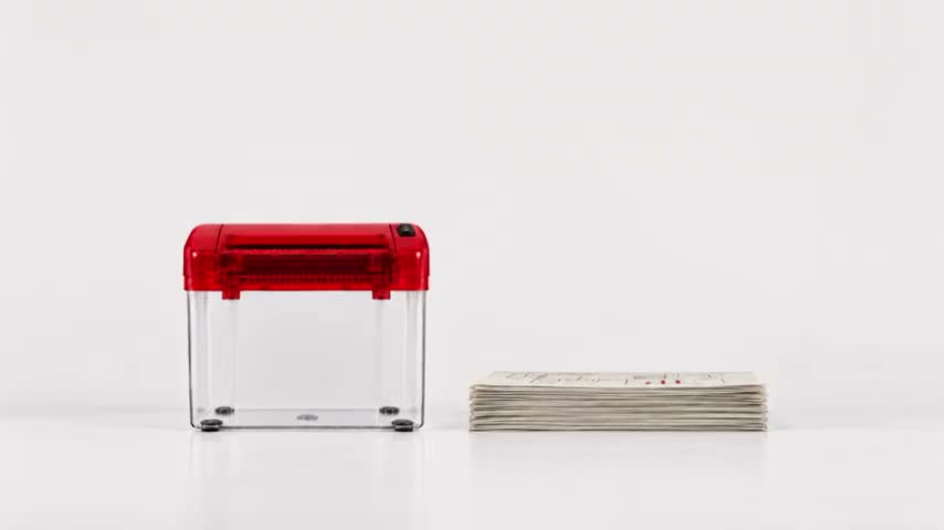 A red paper shredder beside a stack of creative ideas